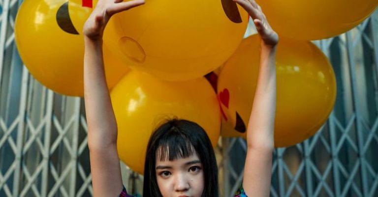 Model - Woman Wearing Blue Top Standing in Front of Yellow Balloons