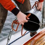 Fishing - Man in Orange Jacket and Gray Pants Holding Black and Red Fishing Rod