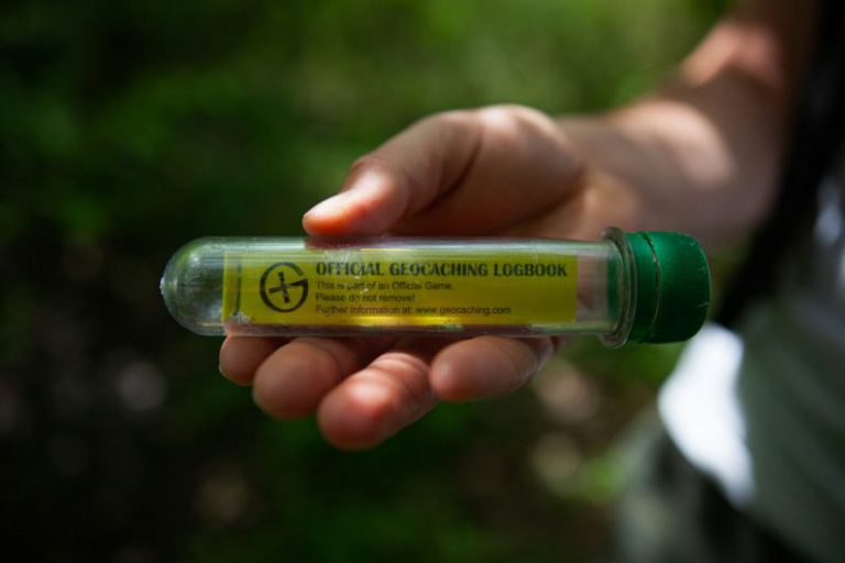 Geocaching - person holding yellow and green plastic bottle